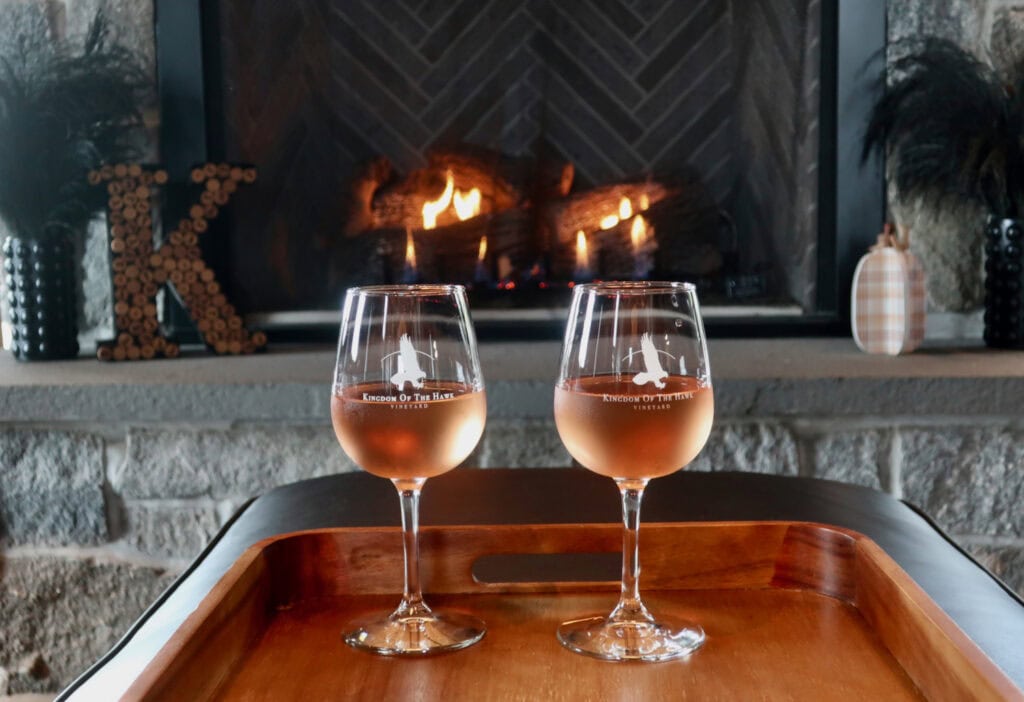 Romantic Kingdom of The Hawk Vineyard with two glasses of wine in front of fireplace